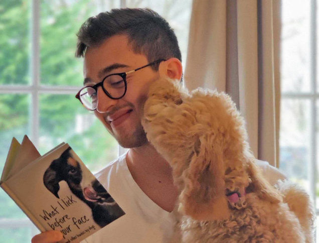 Dog licking person's face with book