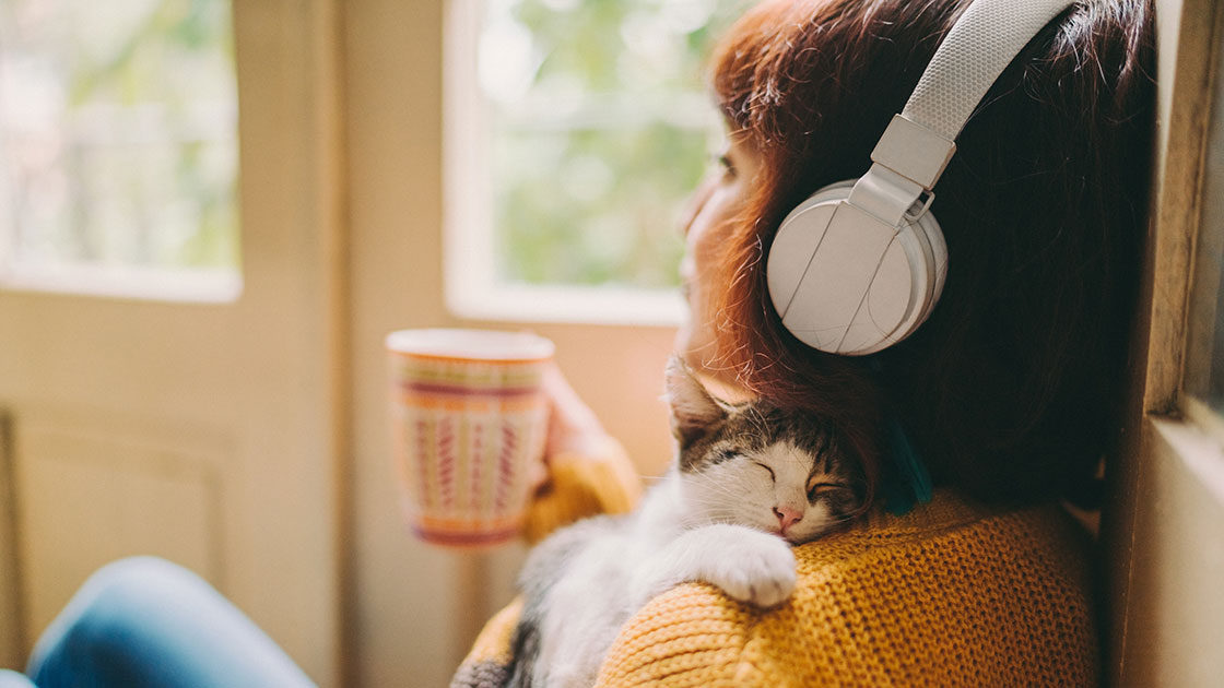 Person listening to headphones with cat